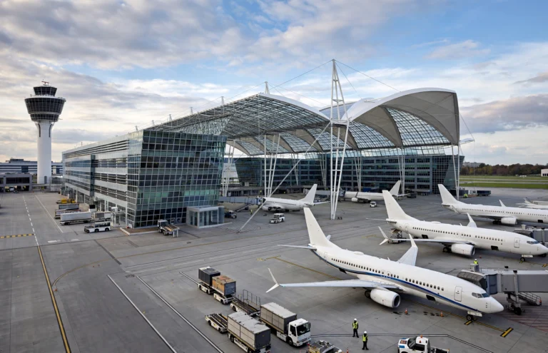 Außenansicht des Flughafens München mit modernem Terminalgebäude und Flugzeugen
